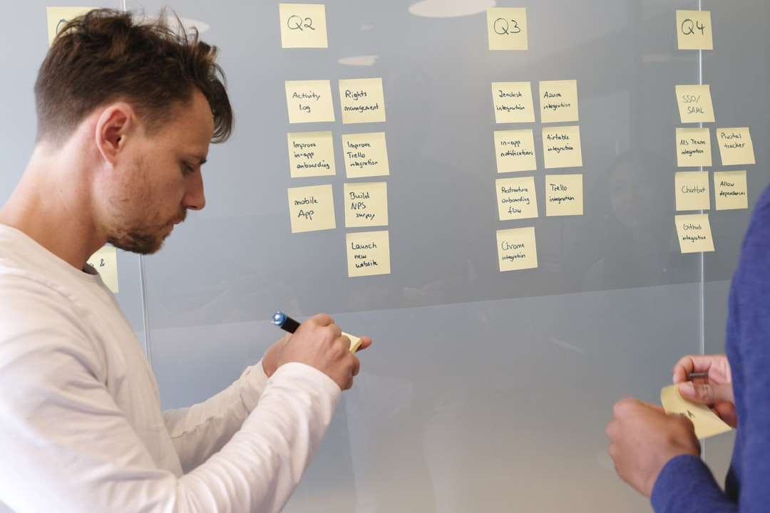 man in white long sleeve shirt writing on white board data analytics team marketing strategy planning