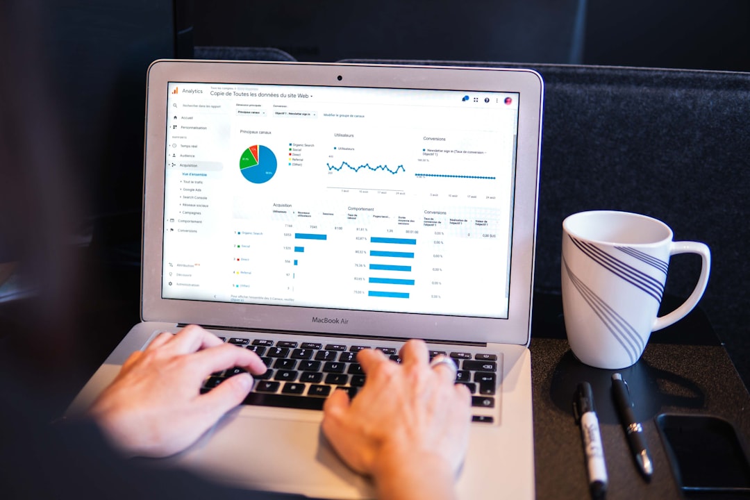 person using macbook pro on black table marketing analytics dashboard laptop screen graphs