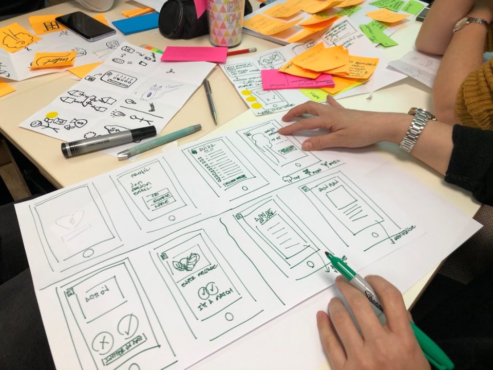 person writing on printing paper creative brainstorming session, digital tablet sketch, design team collaboration, sticky notes board