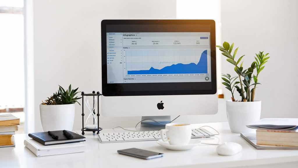 Silver imac displaying line graph placed on desk