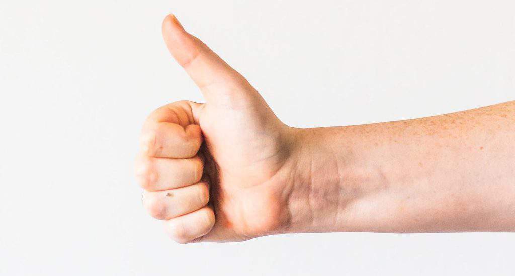 persons right hand doing thumbs up