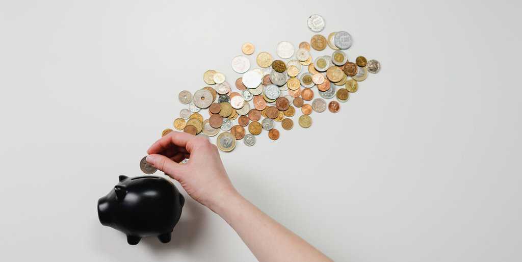 Person putting coin in a piggy bank