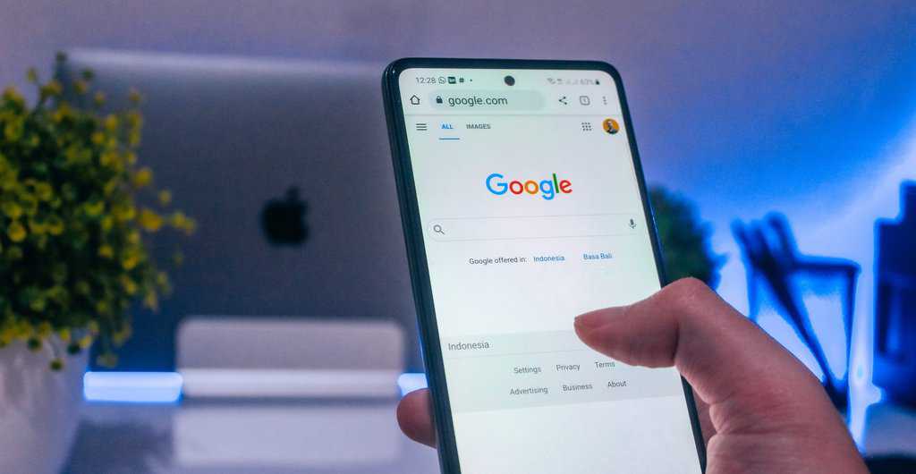 Hand holding phone opening google search looking for something.