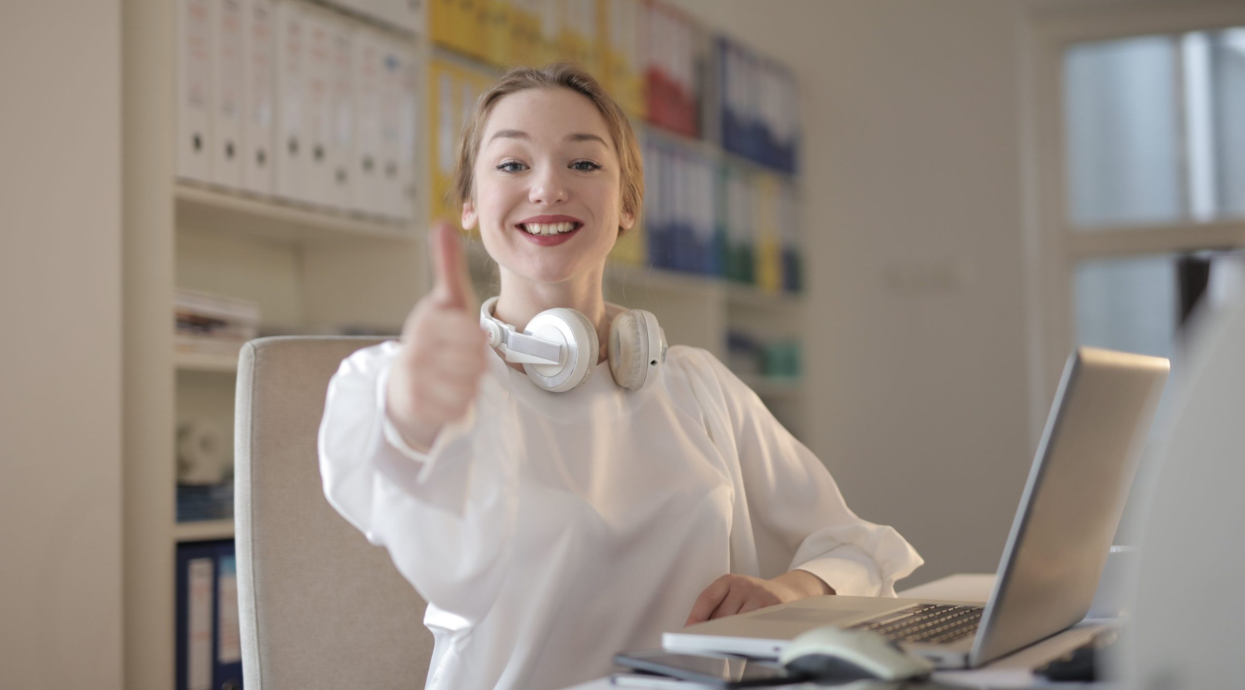 Woman wearing white top while doing thumbs up