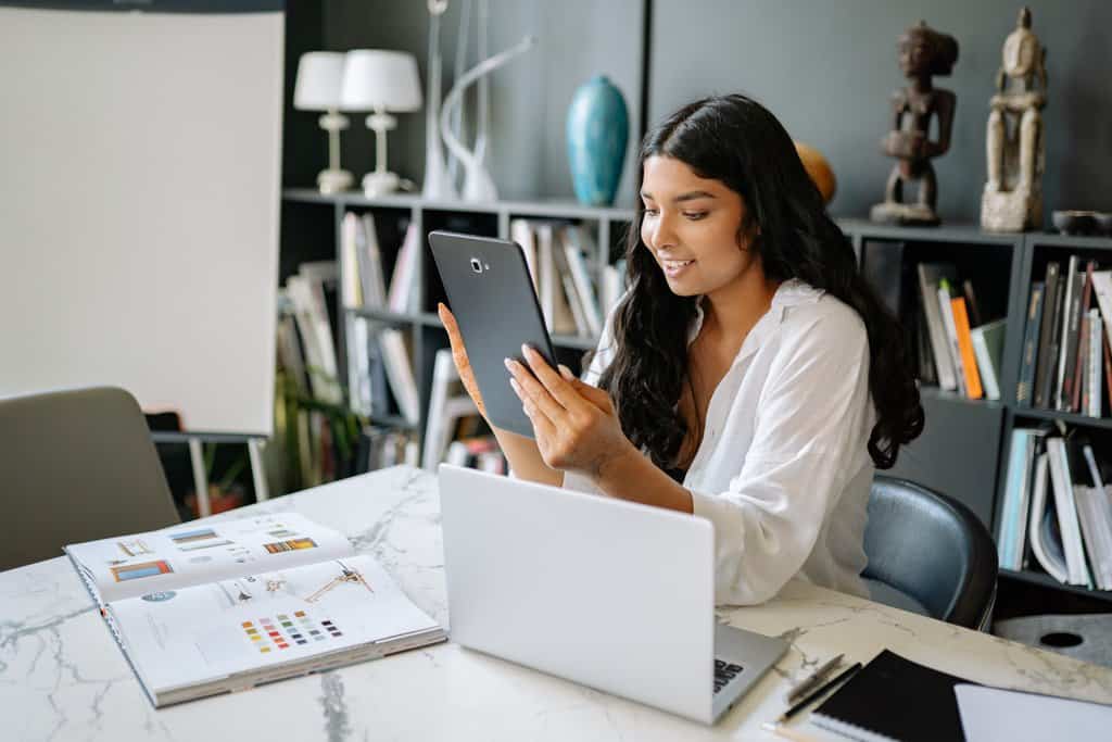  A young woman is sitting at a desk and using a tablet to search for solutions to Facebook login issues.