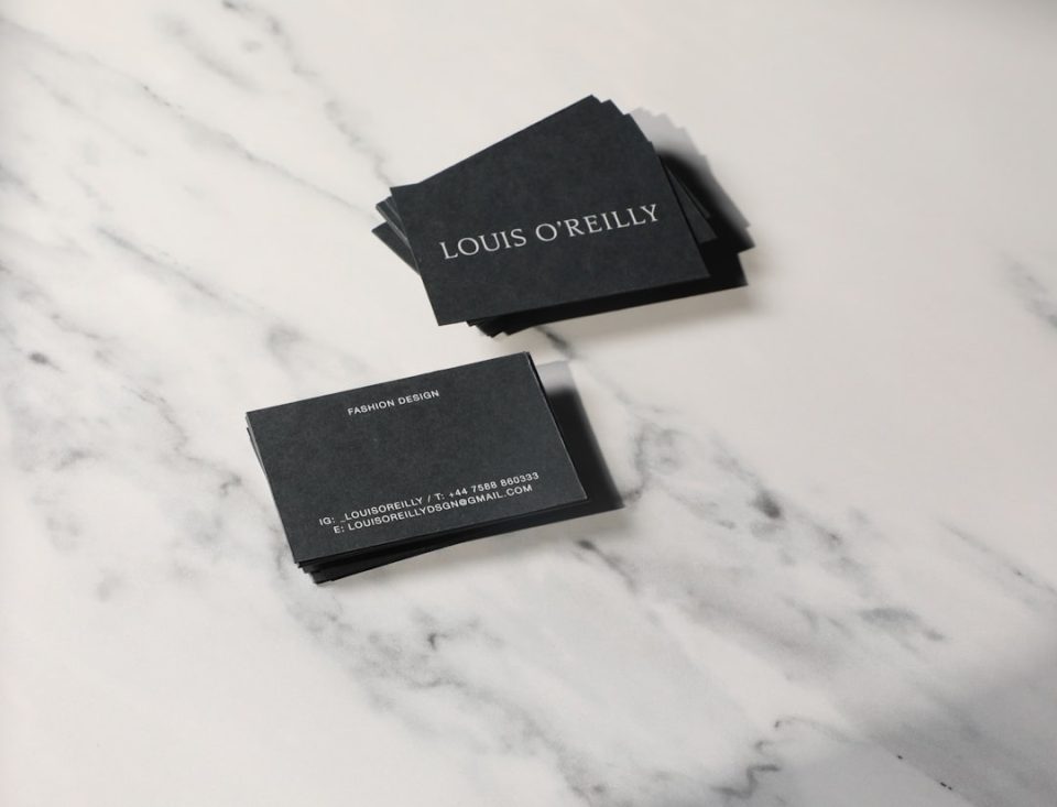 A pair of business cards sitting on top of a marble counter business cards stack, print finishes, matte gloss comparison
