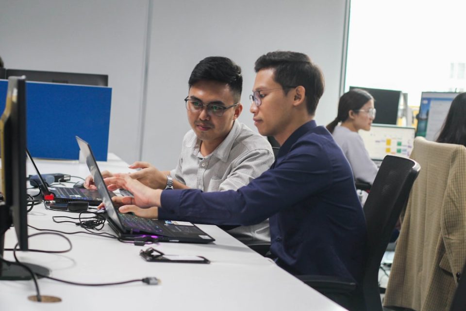 two men sitting at a desk looking at a laptop cybersecurity team, digital defense, SEO analytics
