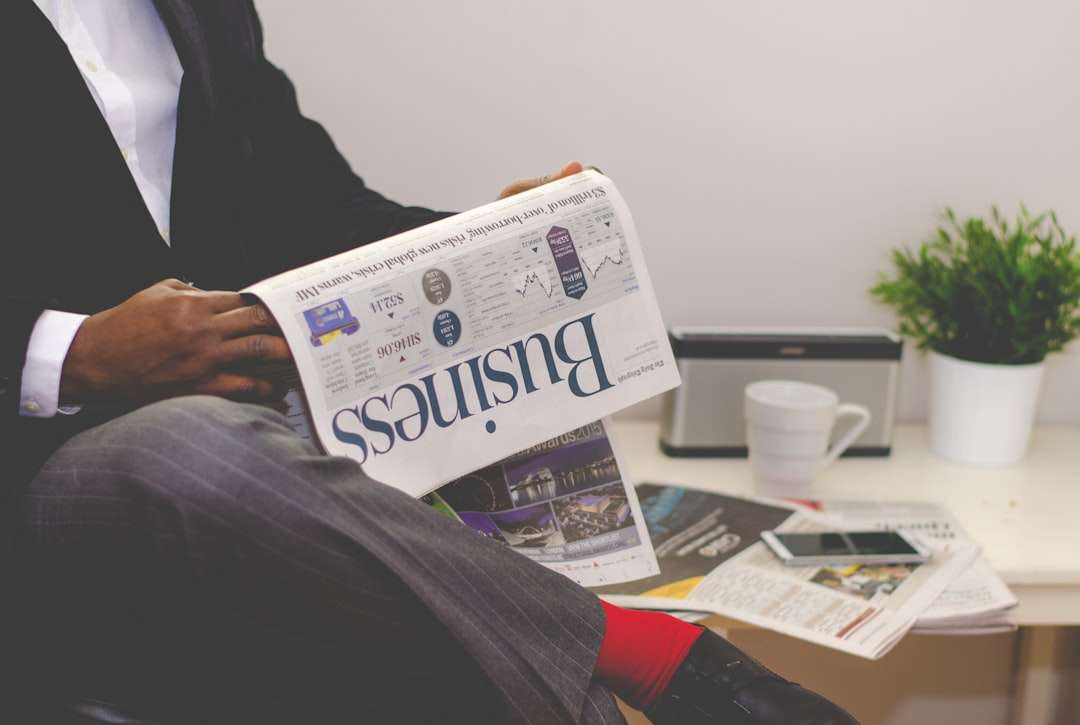 person sitting near table holding newspaper real estate crm, data transition, business tools