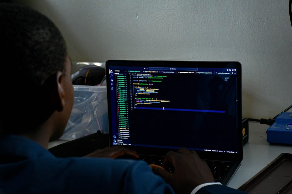 a man sitting in front of a laptop computer ai code assistant cloud ide screen