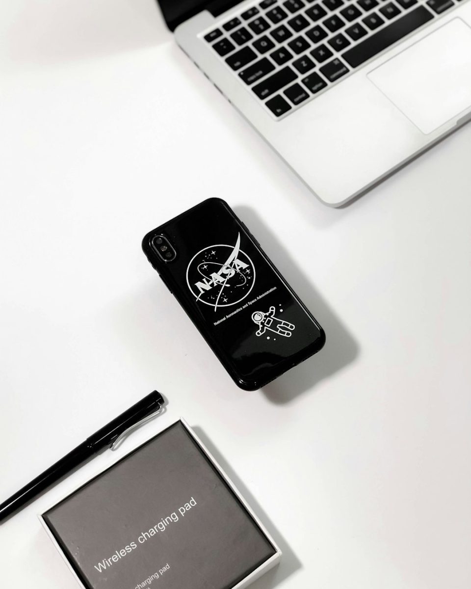 black NASA-printed phone case near MacBook Pro startup branding, logo creation, design tools